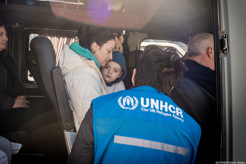 ウクライナから避難してきた人々を乗せたバスを迎えるUNHCR職員
